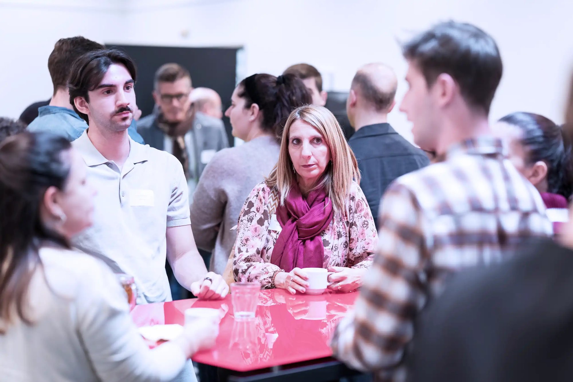 Menschen die um einen Tisch stehen und diskutieren.