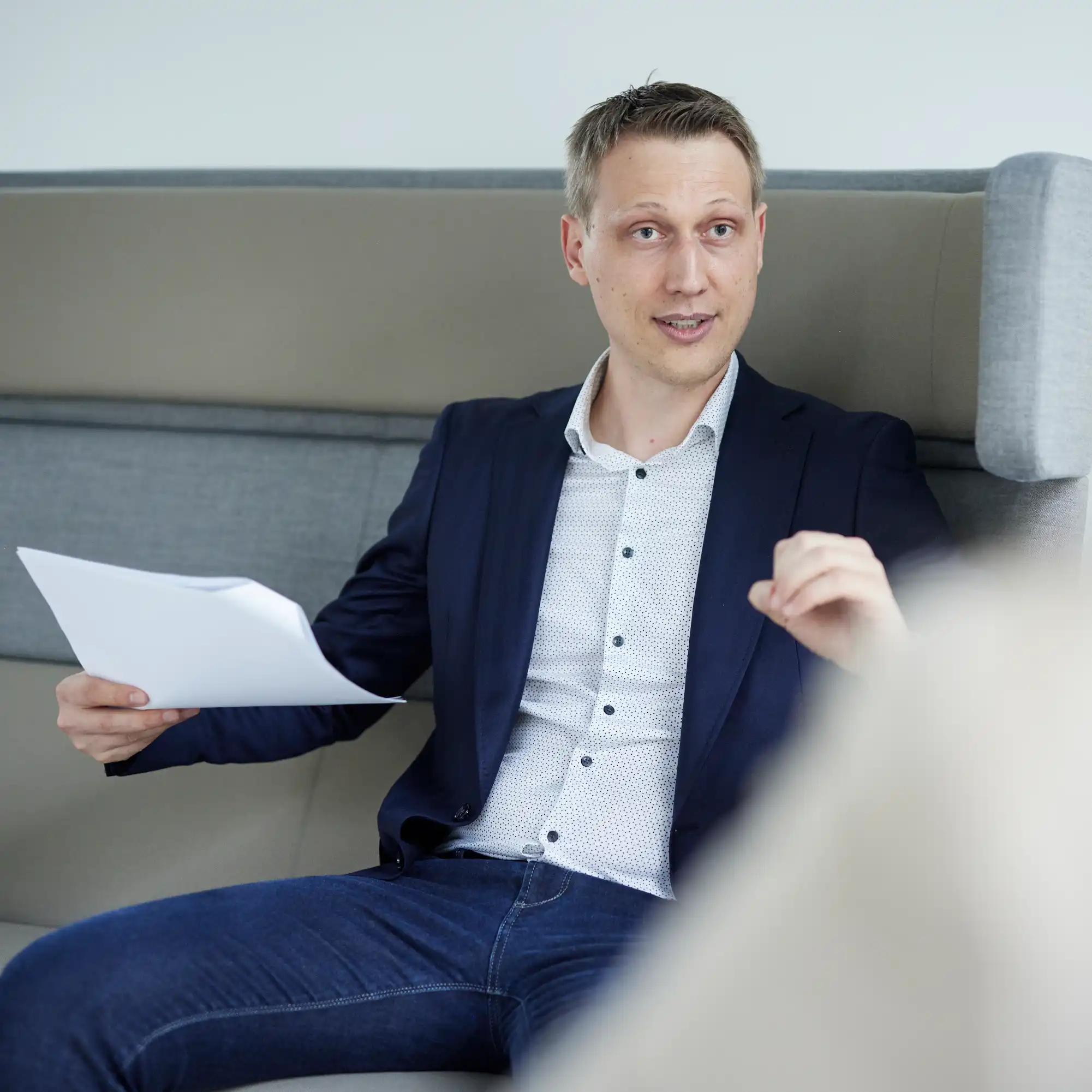 Felix Leimbach in Jeans und weissem Hemd auf Sofa